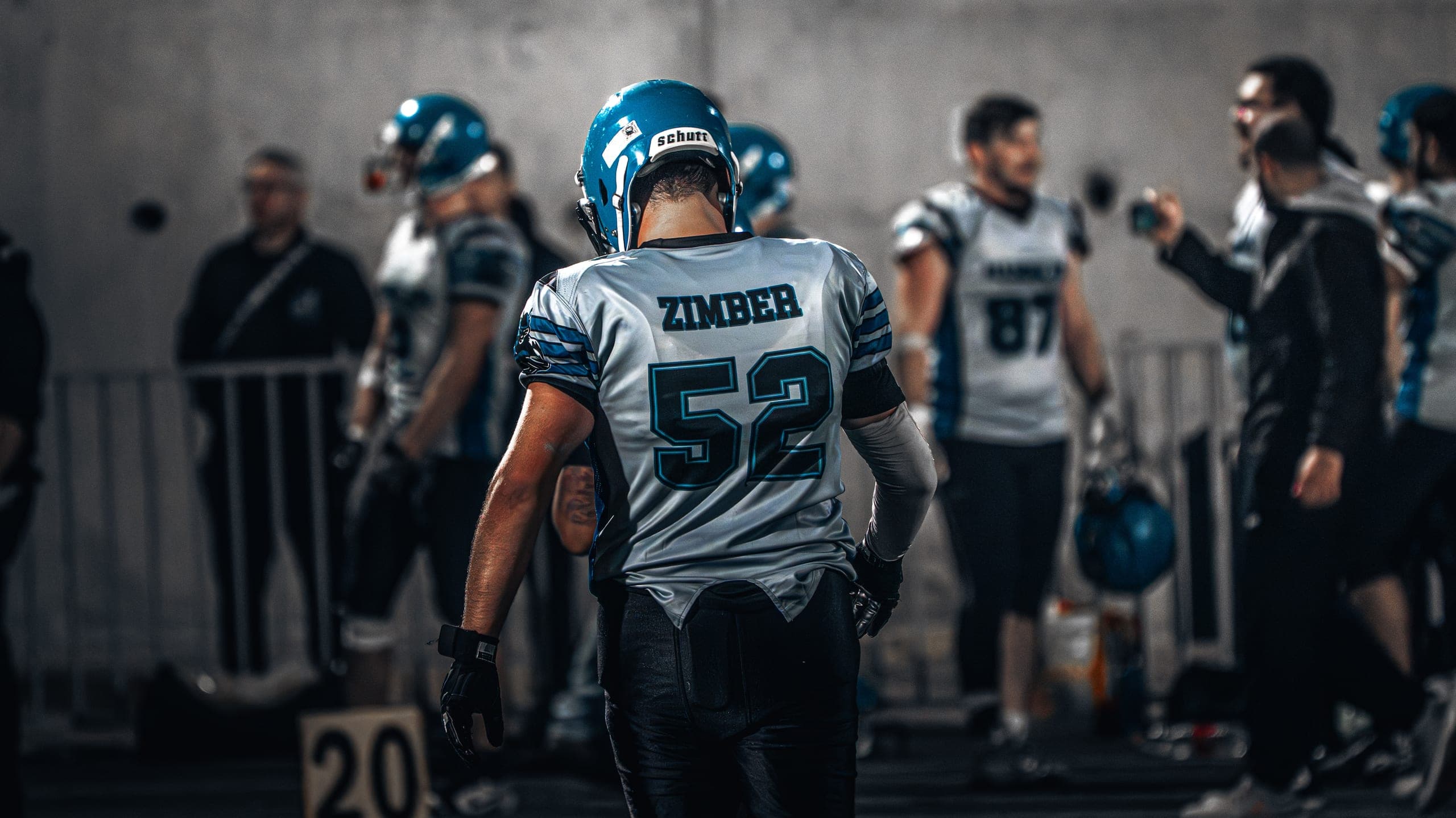 Football player walking through a tunnel before a game, jersey reading Zimber 52